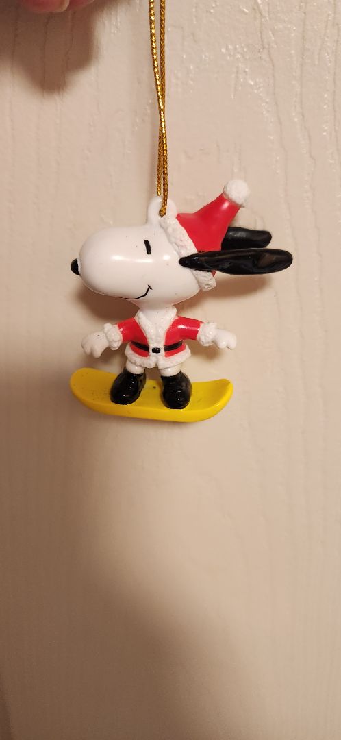 Charles Schultz Snoopy wearing Santa suit, riding snowboard ornament