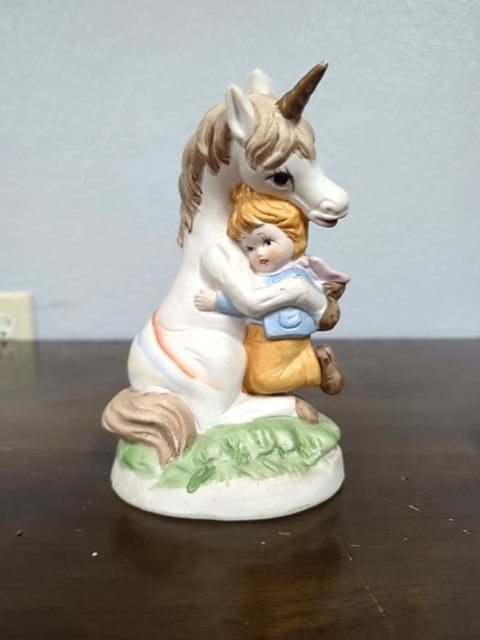 Ceramic unicorn hugging a child