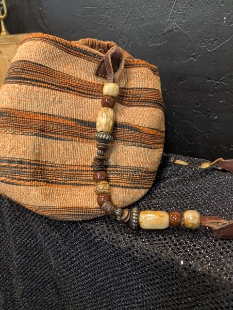 woven bucket bag featuring a chunky beaded handle and earthy striped tones
