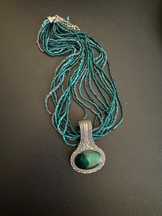 Multi strand teal seed bead with silver tone pendant necklace